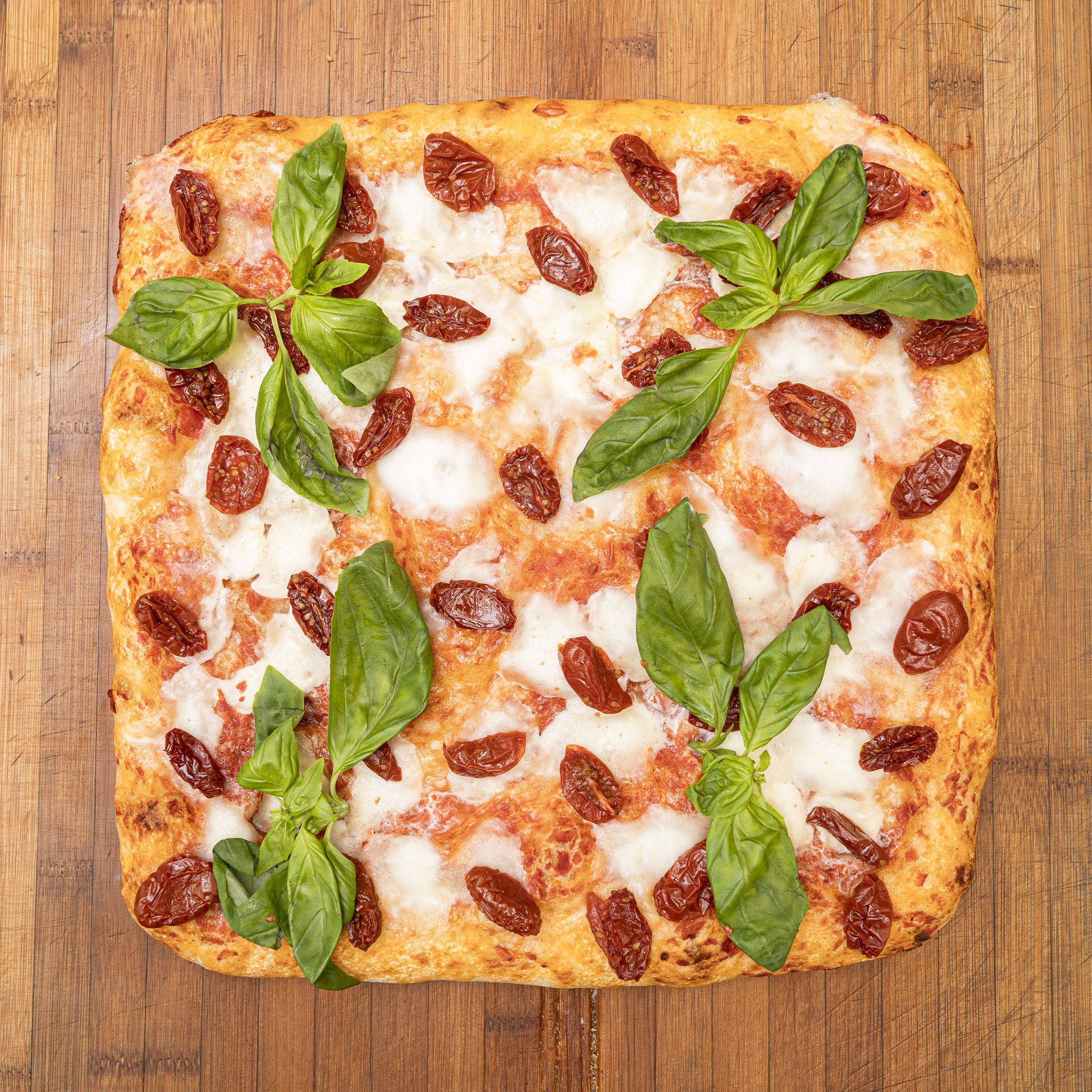 TRANCIO DI PIZZA CON MOZZARELLA DI BUFALA, POMODORINI, BASILICO E EVO