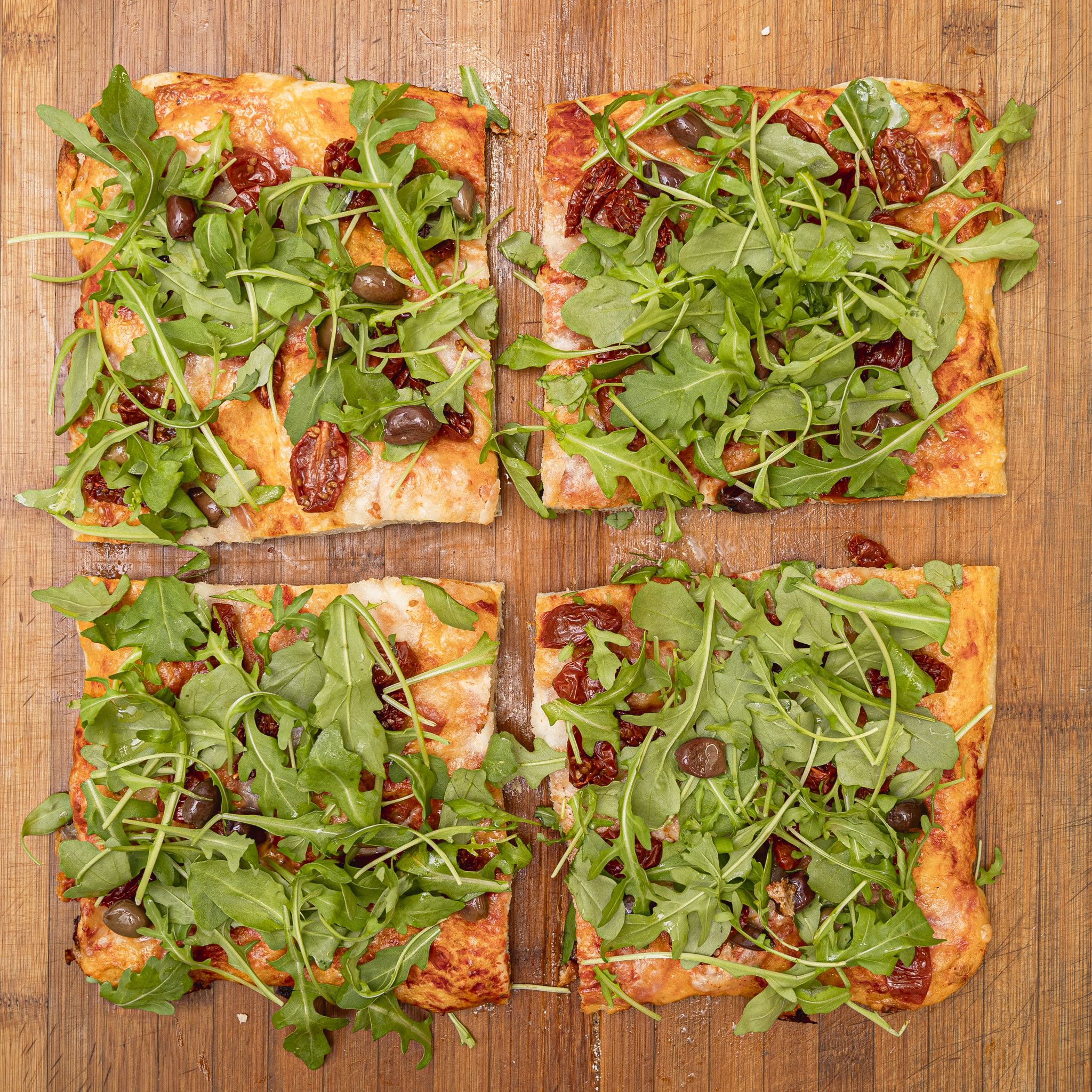 TRANCIO DI PIZZA CON POMODORO, MOZZARELLA DI BUFALA, OLIVE DI TAGGIA, RUCOLA E GRANA