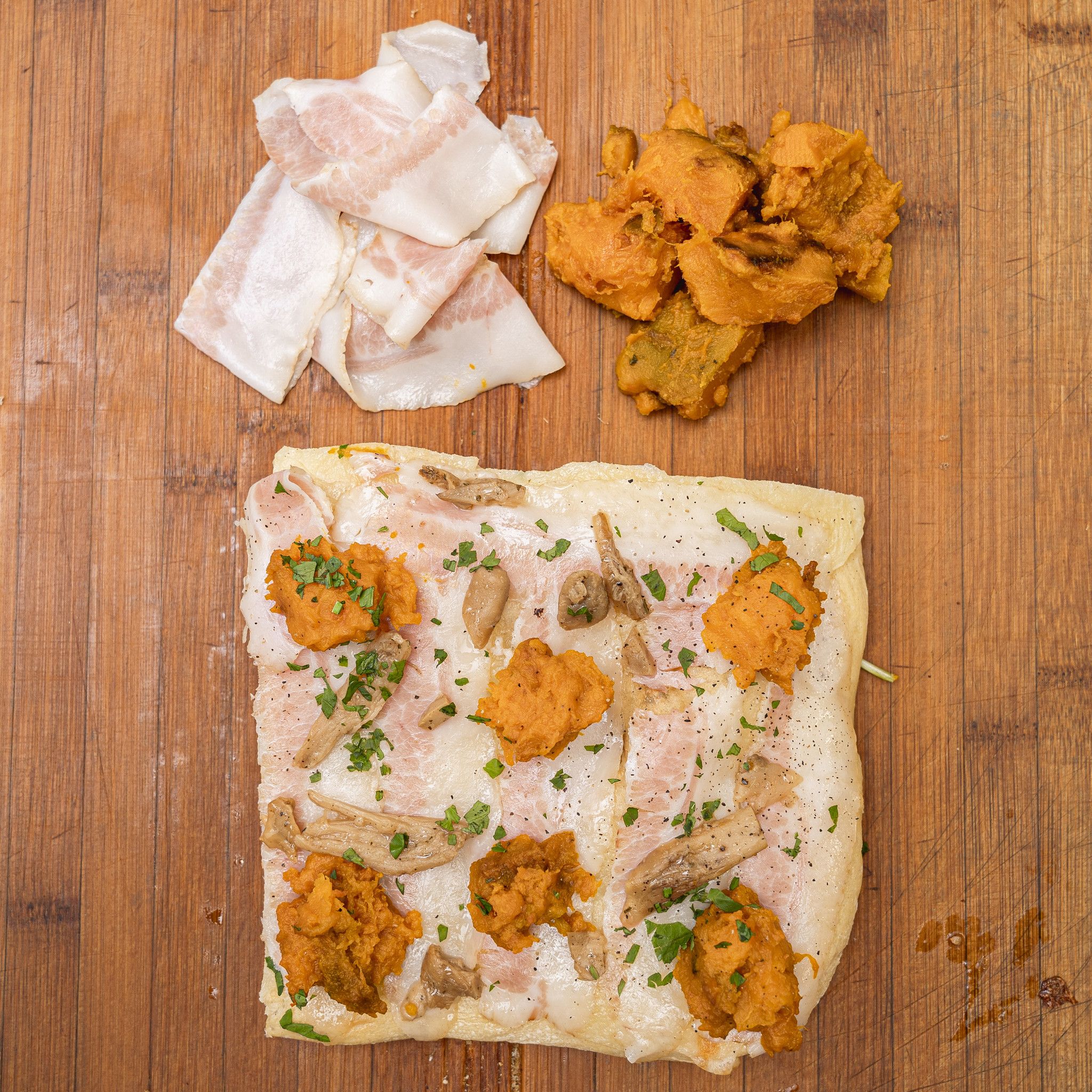 TRANCIO DI PIZZA BIANCA CON MOZZARELLA, ZUCCA, GUANCIALE, PORCINI, PEPE NERO E PREZZEMOLO