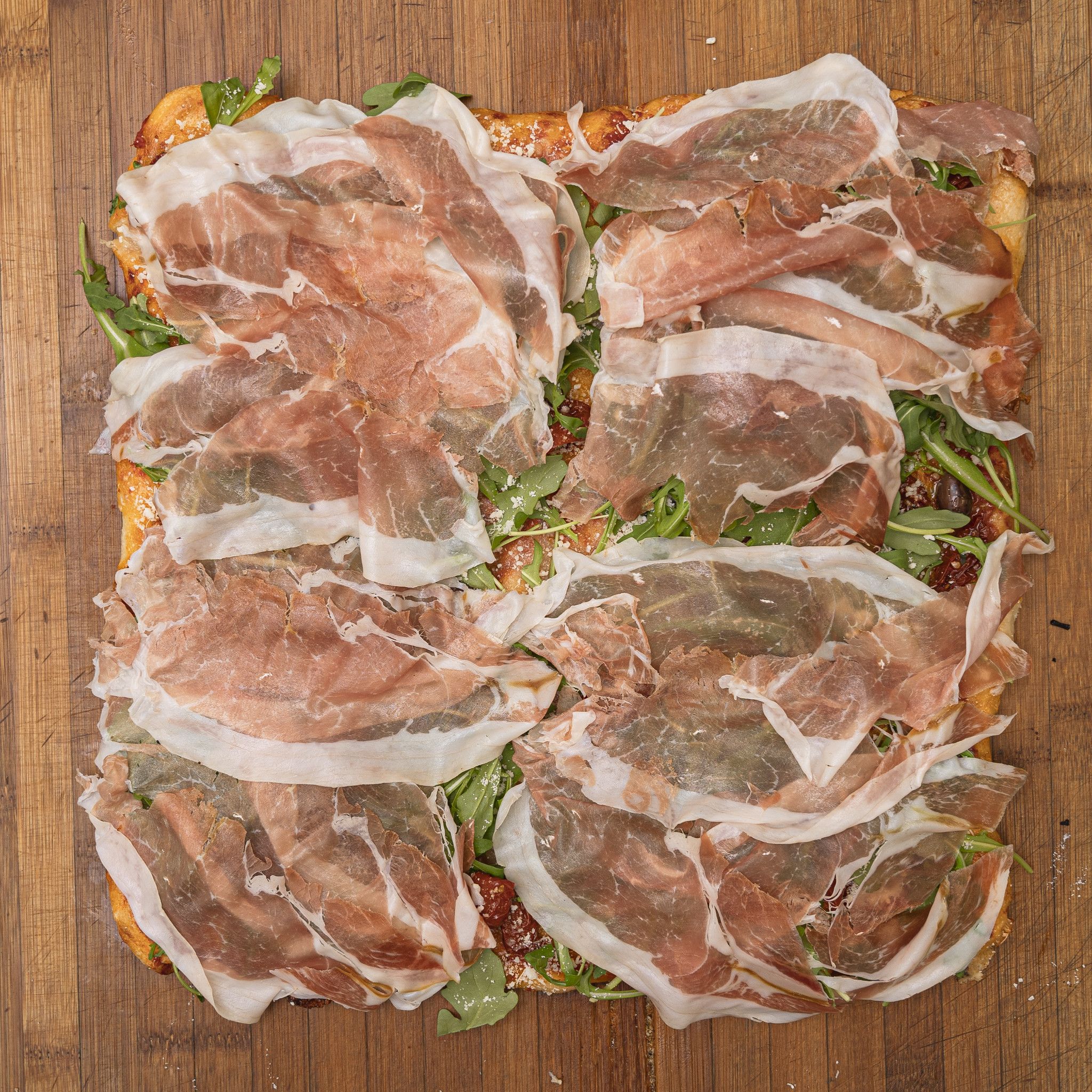 TRANCIO DI PIZZA CON POMODORO, RUCOLA, BUFALA DOP, OLIVE DI TAGGIA, GRANA E CRUDO DI PARMA