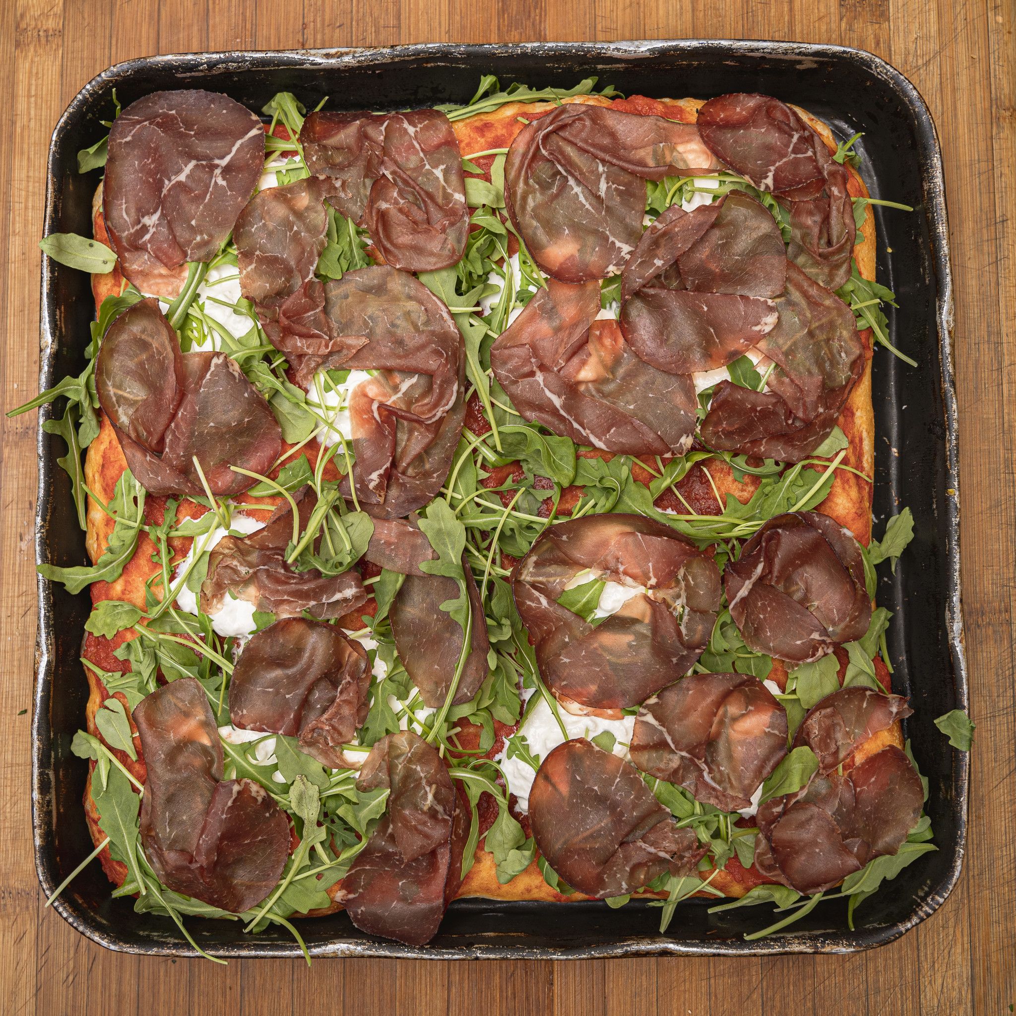 TRANCIO DI PIZZA CON POMODORO, STRACCIATELLA, RUCOLA E BRESAOLA PUNTA D' ANCA
