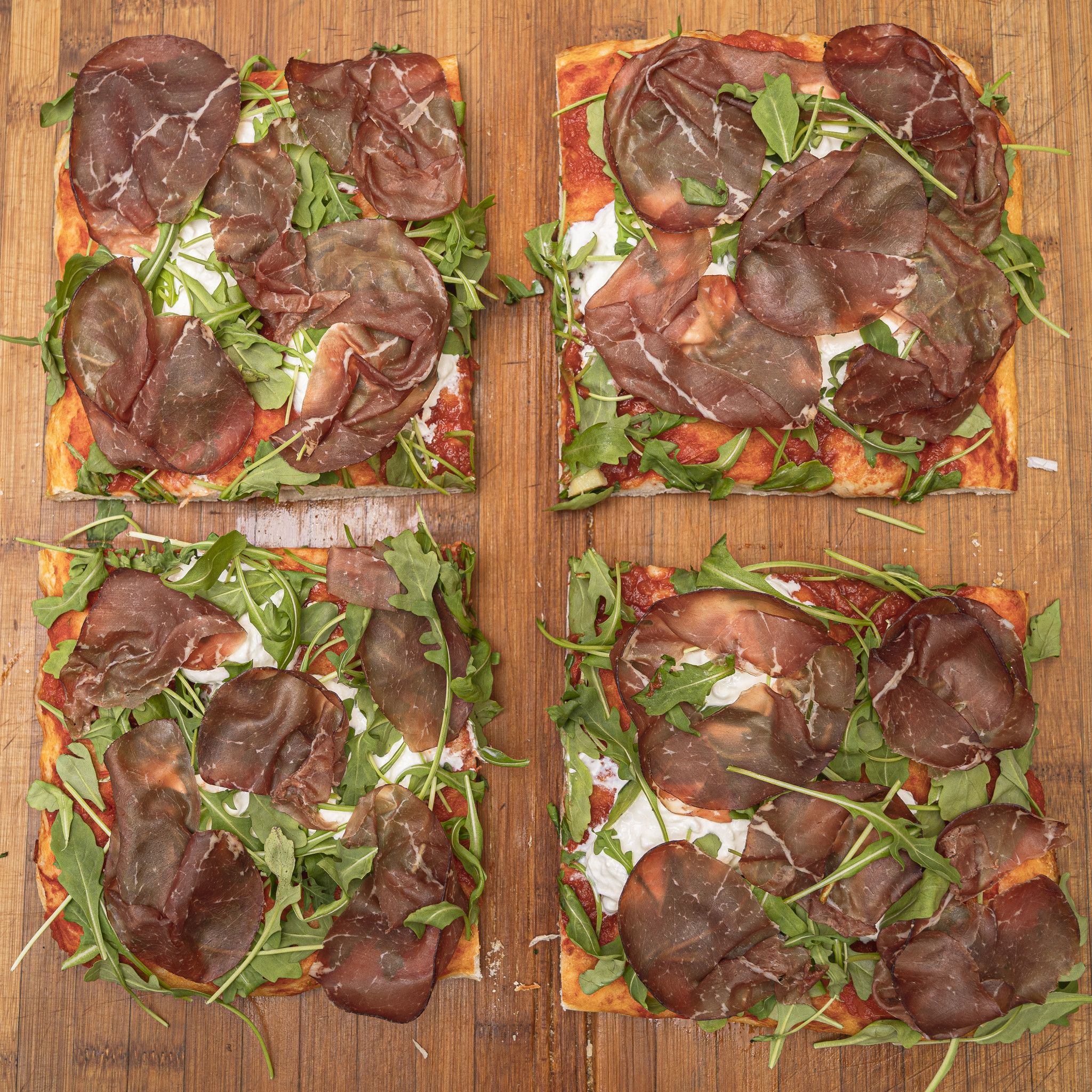 TRANCIO DI PIZZA CON POMODORO, STRACCIATELLA, RUCOLA E BRESAOLA PUNTA D' ANCA