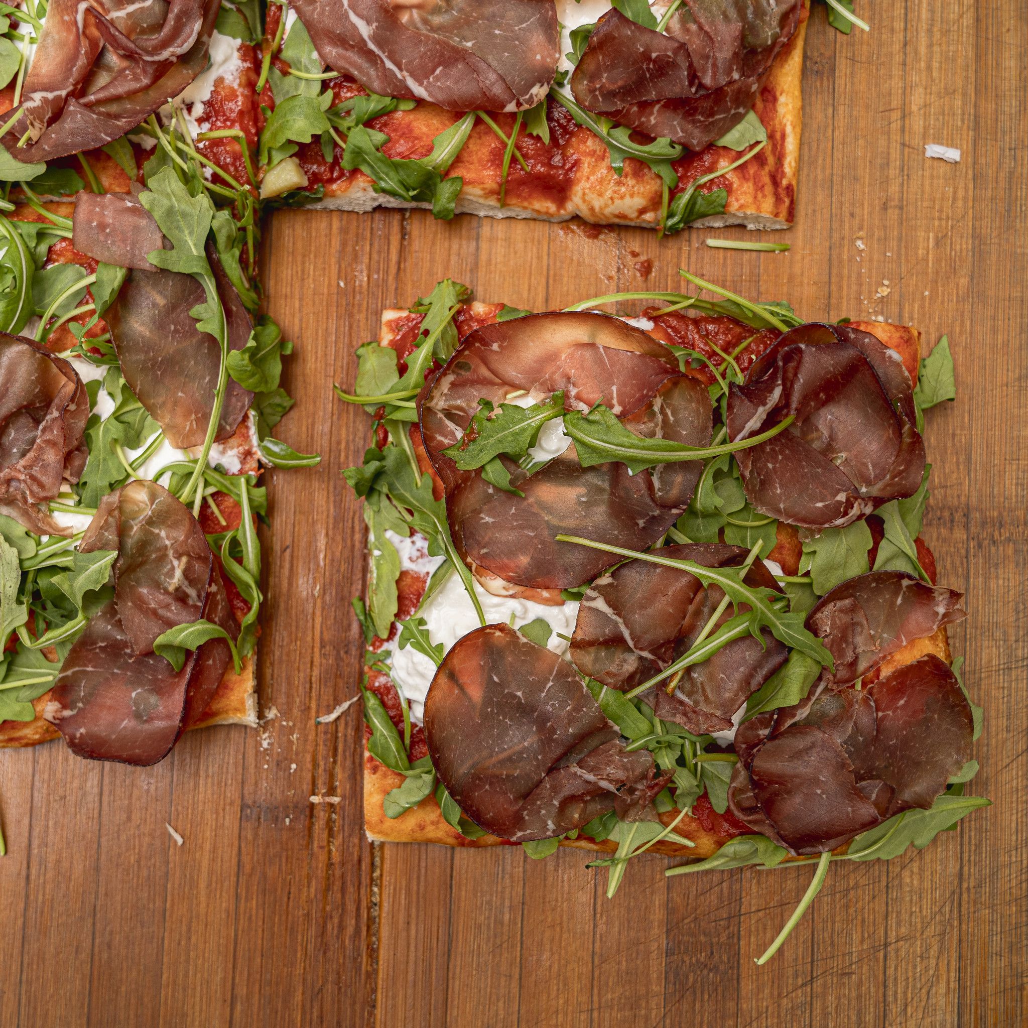 TRANCIO DI PIZZA CON POMODORO, STRACCIATELLA, RUCOLA E BRESAOLA PUNTA D' ANCA
